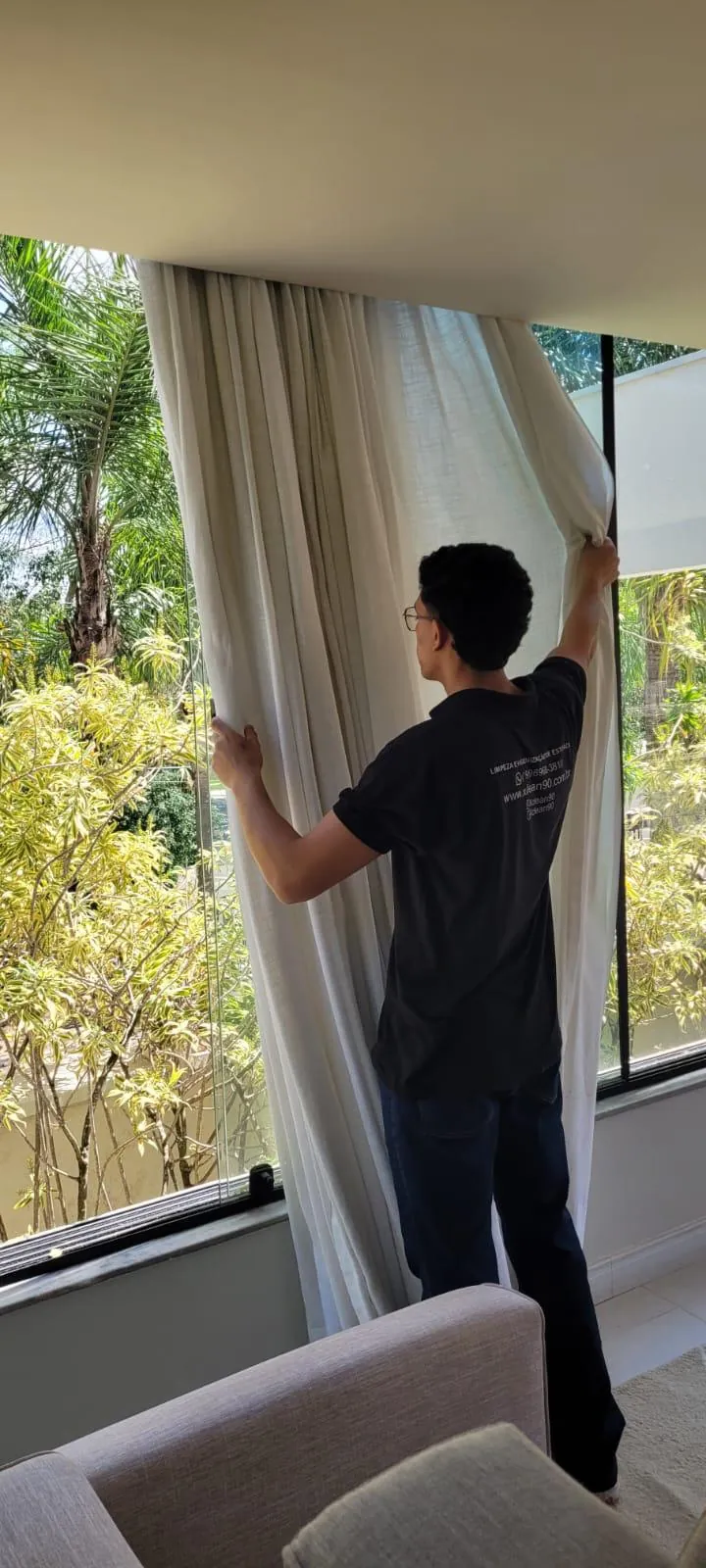 Técnico da Xclean90 higienizando cortina em sala com luz natural